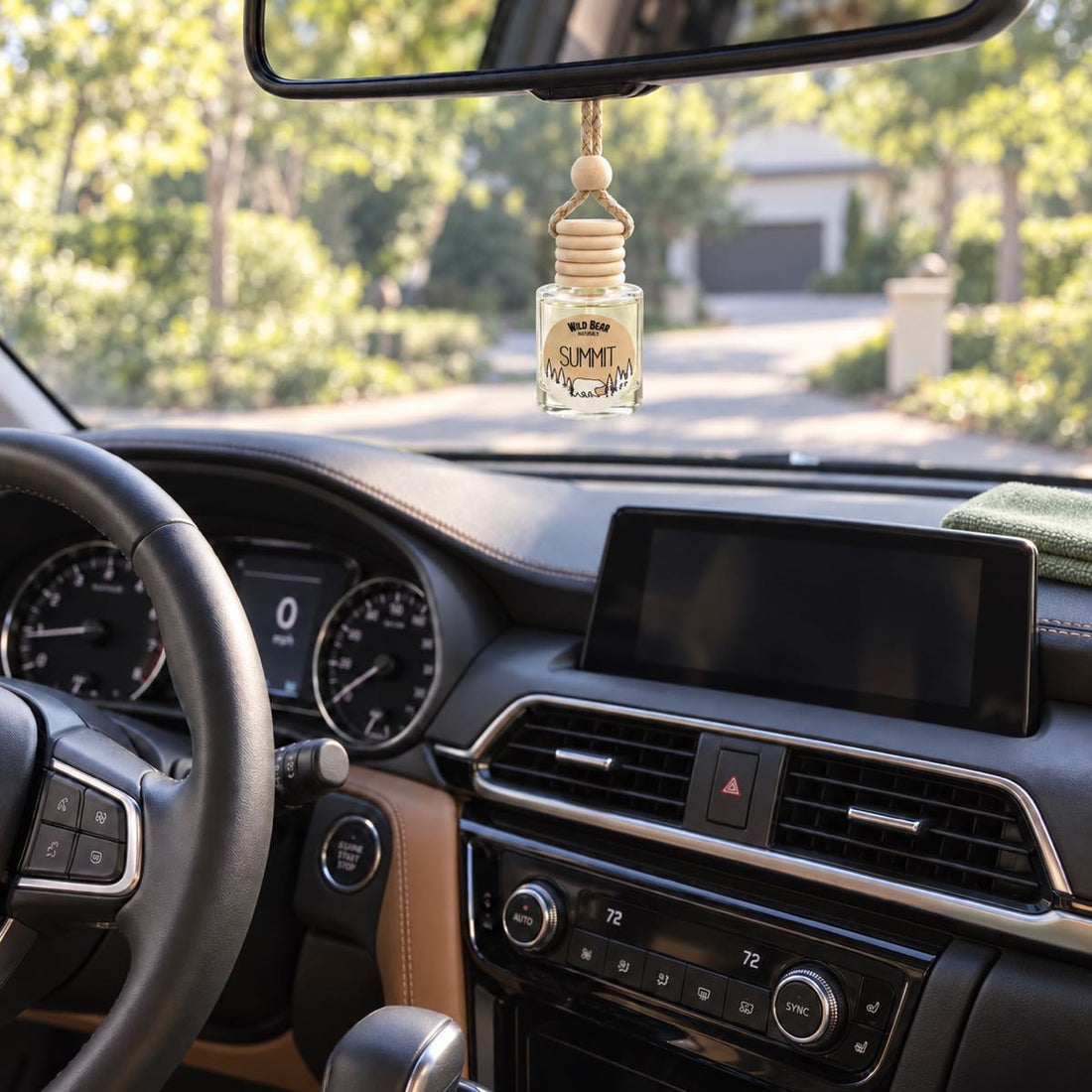 A Summit car freshener hangs from the rearview mirror above a freshly detailed dashboard, with a folded green microfiber cloth on the passenger side.