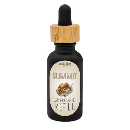 A bottle of Wild Bear Market Summit Car Freshener Refill, featuring a black glass bottle with a light wood dropper cap and a cream-colored label.